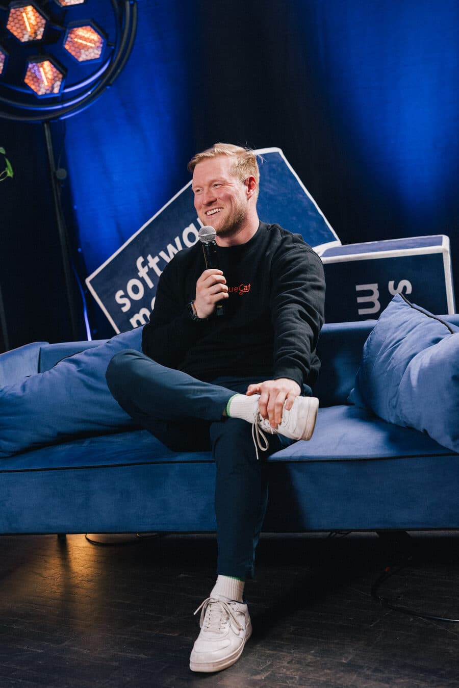 Perttu on a couch on stage at App.js Conf, holding a microphone